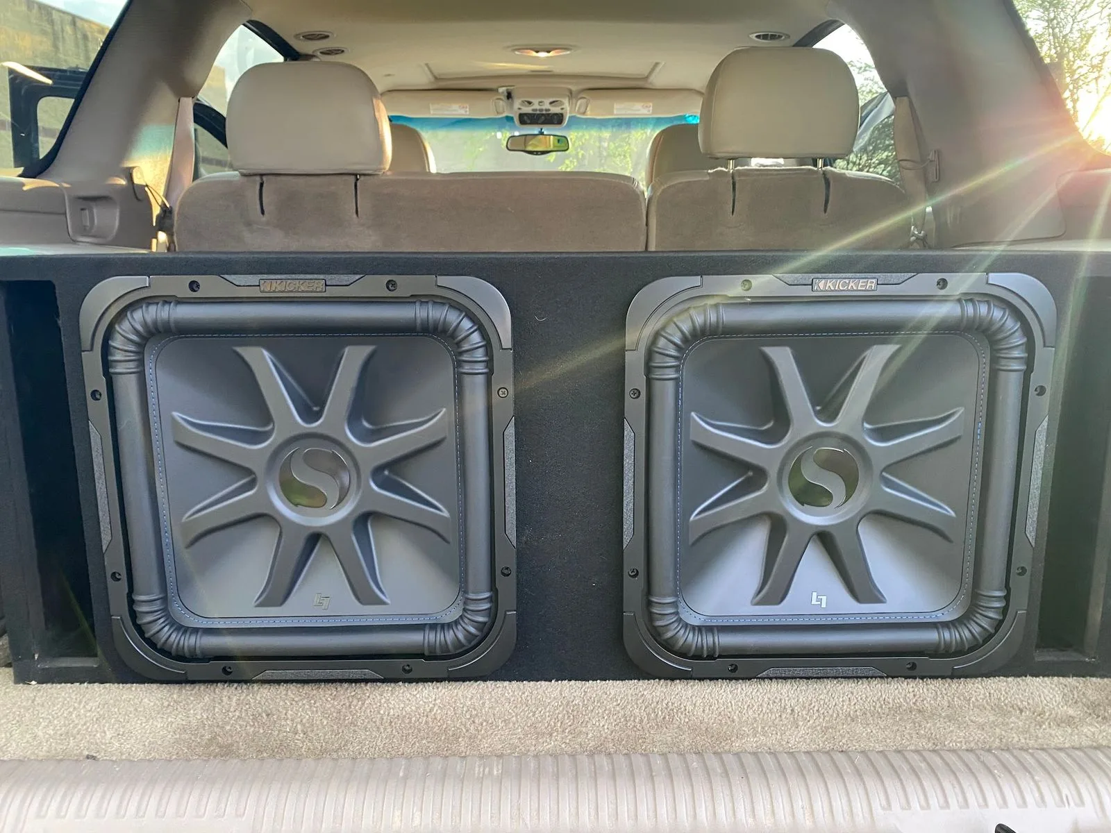Two Kicker subwoofers in a custom box in an SUV cargo area